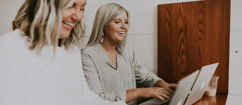 Two women sitting at a desk, engaged in conversation