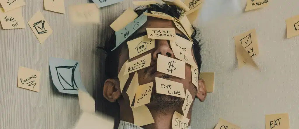 Man with multiple stickers covering his face and head, symbolizing information overload and mental overwhelm