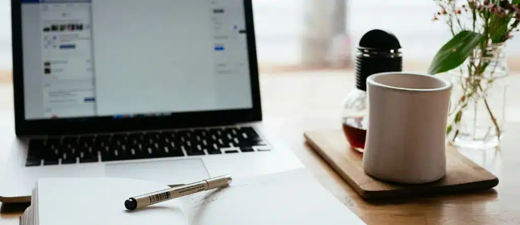 An open laptop with a book and pen placed in front of it, suggesting a workspace or study environment.