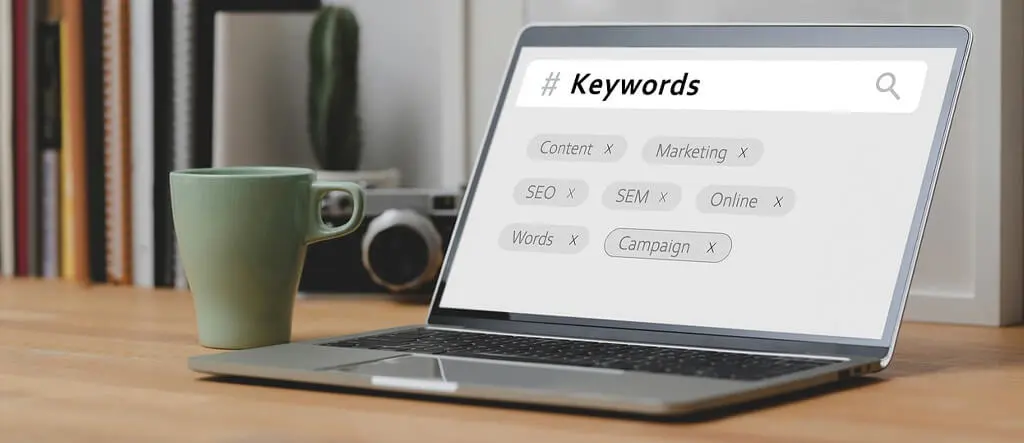 A laptop screen showing the word "keyword" in a search bar with several keywords listed below, representing keyword research for niche sites.