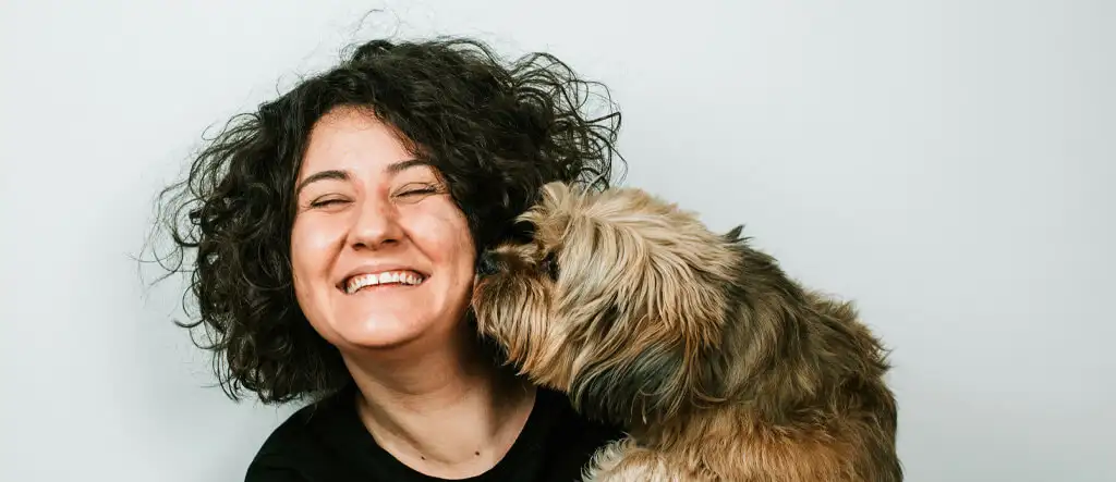 Smiling woman training her dog outdoors, reinforcing their bond through pet care and obedience.