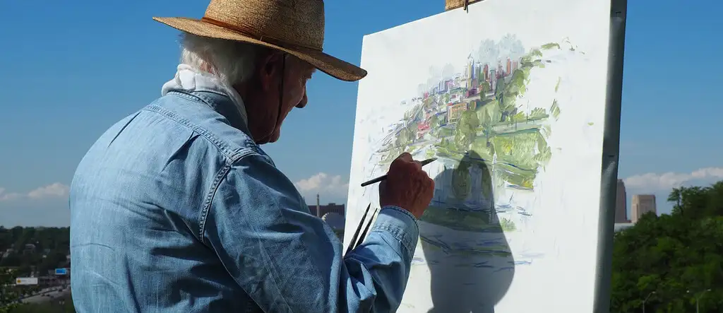 Man painting a landscape outdoors, enjoying art as a relaxing retirement hobby.