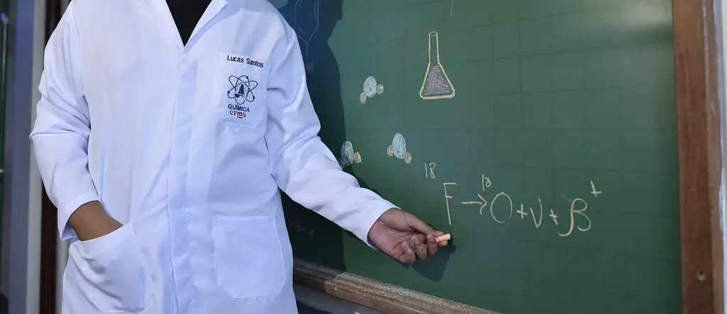 A man writing on a blackboard, demonstrating a teaching session or educational concept in a classroom setting.