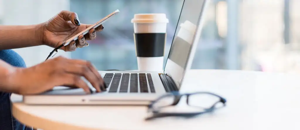 Woman shopping online using a laptop and mobile phone, symbolizing affiliate marketing opportunities.