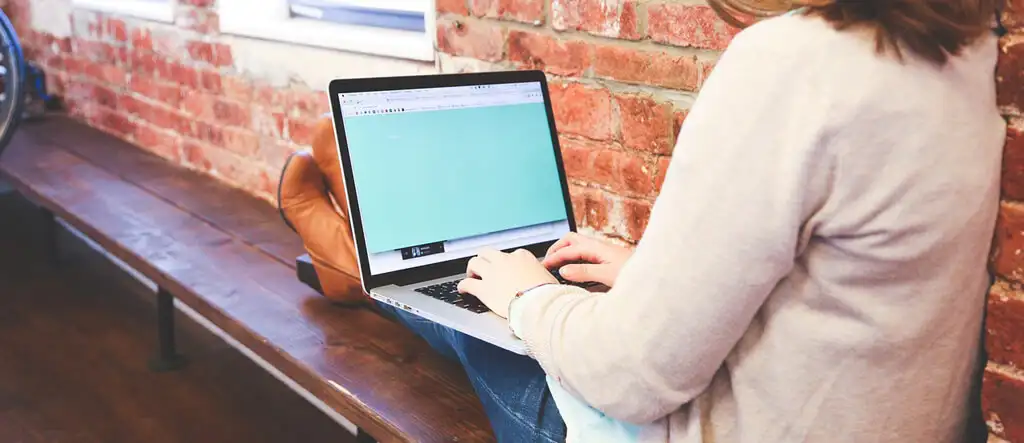 A woman sitting at home using her laptop, representing flexibility and opportunities in freelancing for seniors and retirees.