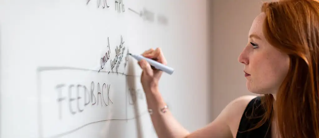 A woman writing on a whiteboard, symbolizing planning and strategy for successful freelance writing.