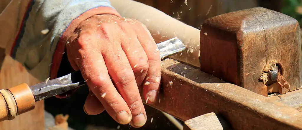 A retiree woodworking in a workshop, crafting a wooden project with hand tools.