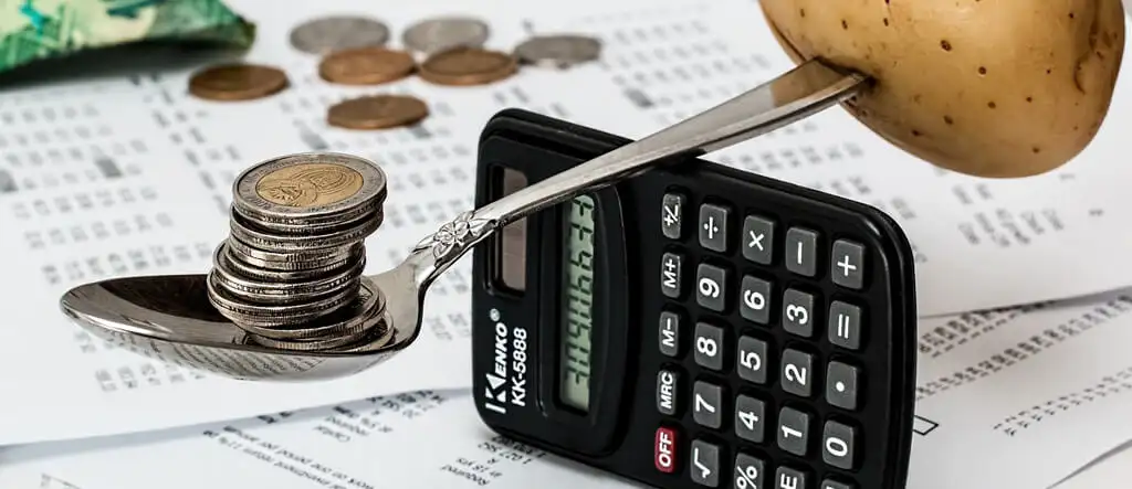 Coins, a calculator, and shopping dockets placed on a table, symbolizing financial planning and resource alignment.