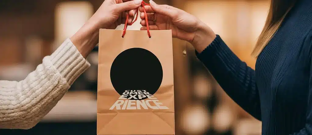 A person handing over a shopping bag labeled 'Customer Experience' to another person, symbolizing the importance of quality and value in online sales.