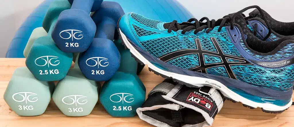 Workout equipment including gym shoes, hand weights, and wrist weights for a fitness routine.