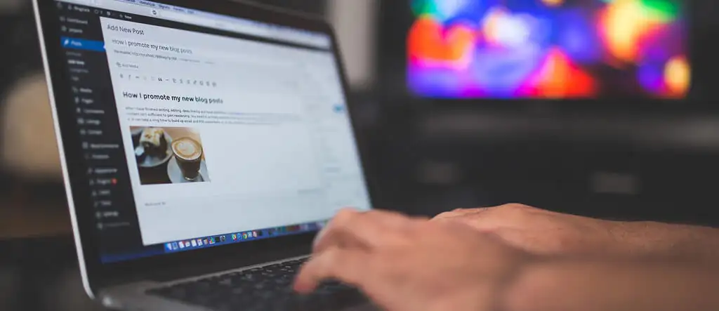 Person using a laptop to post a blog entry, representing the act of publishing a blog post online.