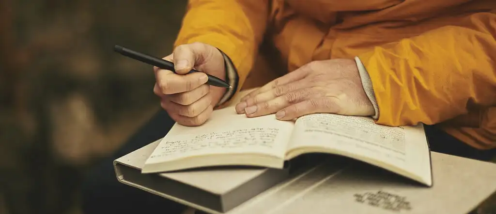 A close-up of hands writing in a journal with a pen, set with a warm and cozy atmosphere